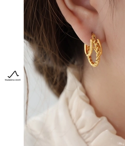 Detail of gold-plated stainless steel twisted rope hoop earring worn by a model