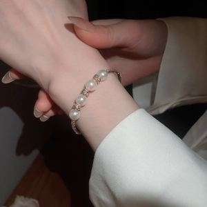 Detail of layered pearl bracelet with rose gold diamond spacers on model's wrist