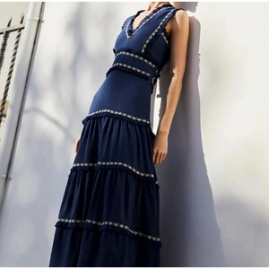 Détail de la robe longue marine avec broderie géométrique et ourlet à volants