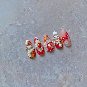 Detail view of 3D strawberry dessert press-on nails with cream and bow design