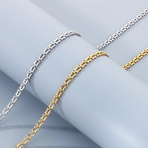 Detailed view of rectangle link chains in gold and silver finish on a blue stand