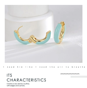 Detail of gold hoop earrings with light blue enamel finish on white pedestal
