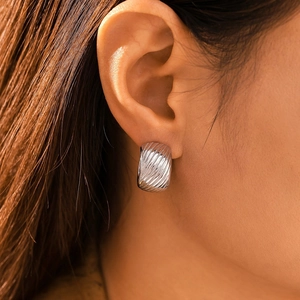 Modern C-shaped silver textured earrings in stainless steel worn by a model