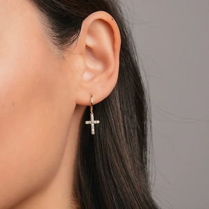 Close-up of gold-plated cross hoop earrings with sparkling cubic zirconia on model