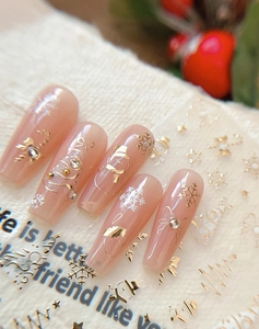 Macro shot of nude Christmas nail stickers with gold snowflakes and bow designs