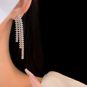 Close-up of silver tassel earrings featuring sparkling crystal fringe on a model