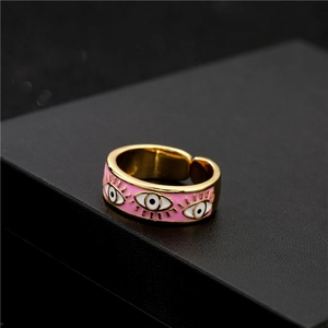 Adjustable golden open ring with pink enamel devil eye patterns on black background