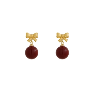Elegant gold bow earrings with dark red beads displayed on a white background