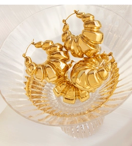 Macro shot of 18K gold plated textured hoop earrings on a striped glass tray