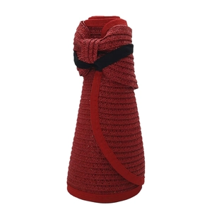 Close-up of a foldable red straw sun hat rolled up for storage with elastic band