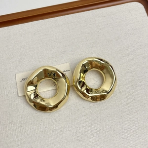 Gros plan de boucles d'oreilles dorées texturées sur un présentoir à bijoux minimaliste