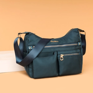 Water-resistant dark teal nylon crossbody bag with multi-pocket design and golden hardware