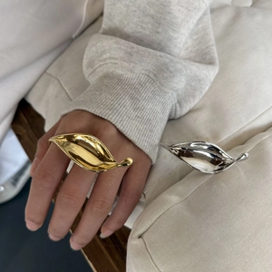 Polished gold and silver leaf shaped open rings showcased on hand and white cushion