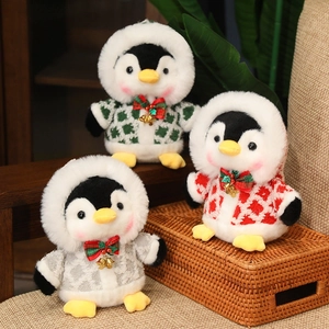 Three plush Christmas penguins in festive plaid hoodies with bells on a rustic wooden background