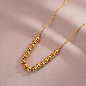 Elegant gold bead necklace with polished metal spheres on a delicate snake chain