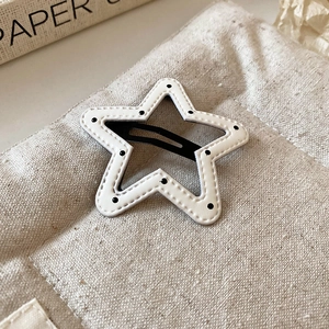 Detailed view of star-shaped hair clip with black polka dots on white leather material