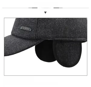 Close-up of winter baseball cap with ear flaps and metal sport emblem on wool fabric