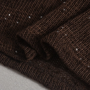 Macro shot of dark brown knit fabric with silver sequins and hollow woven texture