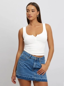 Close-up of white ribbed sleeveless henley tank top with buttons and blue denim skirt