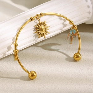 Dettaglio ravvicinato di un bracciale a C placcato oro 18K con ciondoli sole e luna