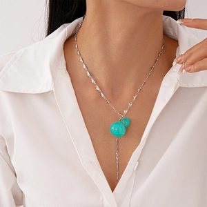 Détail d'un pendentif gourde en résine verte avec chaîne en cœur et longues franges en métal