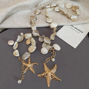 Detail of beaded starfish and shell necklace with iridescent pearl luster and gold charms