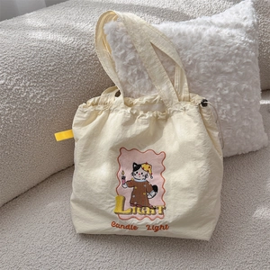 Close-up of cute cartoon cat embroidery on a cream drawstring canvas tote bag