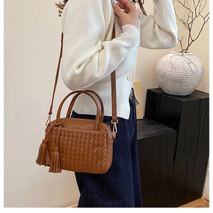 Close-up of deep brown woven texture and stylish fringe charm on a faux leather tote