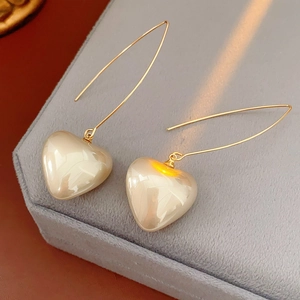 Close-up of vintage golden heart pearl drop earrings on a grey velvet jewelry box