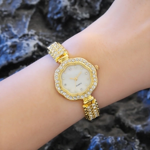 Montre femme dorée avec fleurs en strass et mouvement à quartz sur le poignet