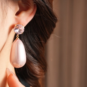 Gros plan de boucles d'oreilles or rose avec pierres roses et perles goutte d'eau