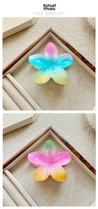 Macro view of gradient plumeria flower hair claws with a glossy resin finish