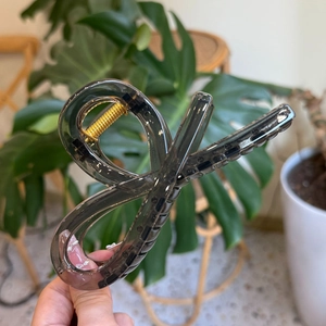 Detail of dark gray translucent shark hair claw clip with golden metal spring