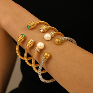 Two-tone stainless steel cable wire cuff bracelet featuring pearls and green gemstones