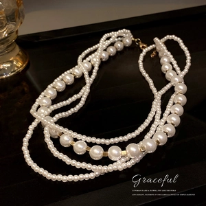 Elegant layered pearl necklace with golden beads on a luxurious dark reflective background