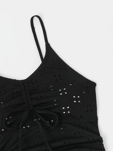 Close-up of black eyelet fabric with drawstring detail and adjustable straps on swimwear
