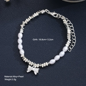 Silver bow pendant pearl bracelet with adjustable chain on blue leather background