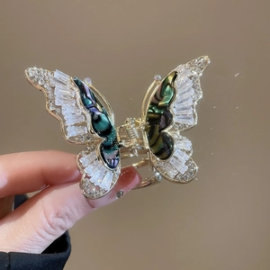 Macro della molletta per capelli a farfalla con zirconi e conchiglia su metallo dorato