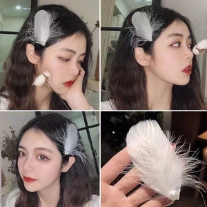 Dettaglio di un fermaglio per capelli in piume bianche con perla su una modella