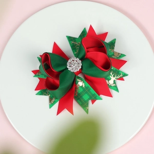 Close-up of a layered Christmas bow hair clip with gold elk prints and rhinestone center