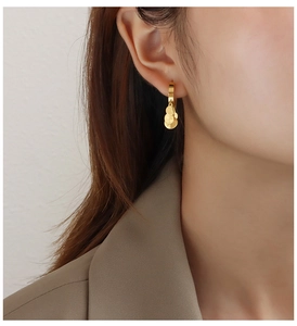 Close-up of golden hoop earrings with five round sequins worn on ear in minimalist style