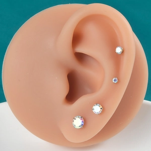 Set of 4 stainless steel stud earrings with round aurora crystals on a silicone ear model