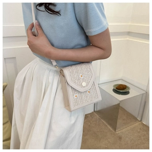 Detailed shot of white straw crossbody bag with daisy embroidery and magnetic flap