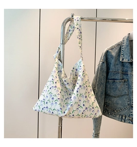 Dettaglio della borsa tote in tela a fiori appesa accanto a una giacca di jeans casual