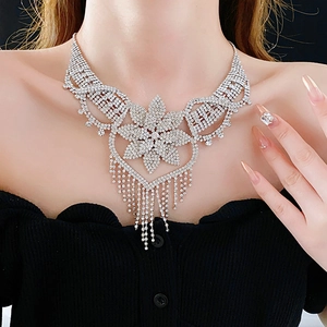 Detail shot of a silver floral rhinestone fringe necklace worn on a black background