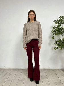 Vista frontale di una modella con maglione grigio e pantaloni a zampa bordeaux