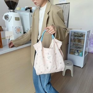 Close-up of pink quilted handbag with cat pattern and blue checkered handles in daily use