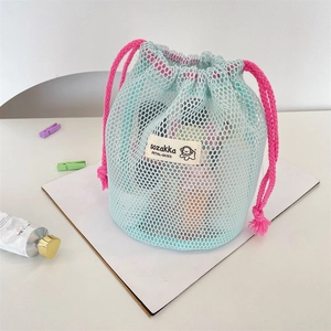 Close-up of mint green mesh drawstring bag with pink cords and brand logo label