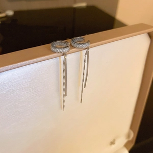 Detail of silver C-shape ear cuff with cubic zirconia and long dangling tassels