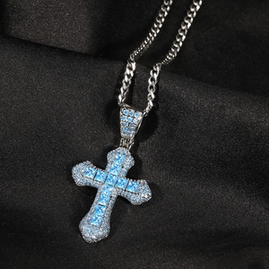 Detailed view of silver cross pendant with blue zircon stones on black silk fabric